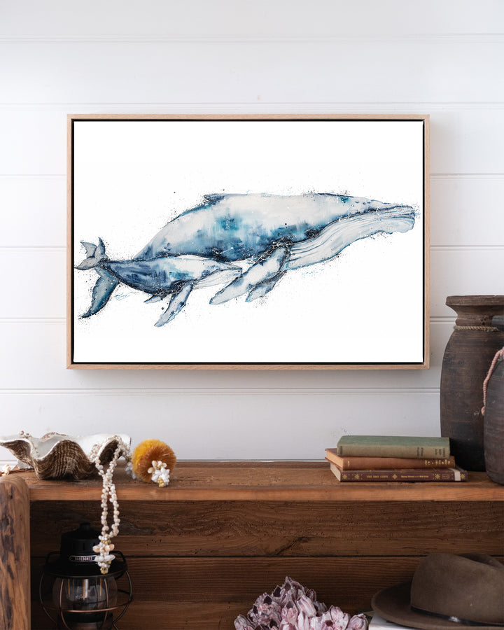 Crazy Love humpback whales fine art print by Stephanie Elizabeth, framed canvas in an oak frame above a bookshelf