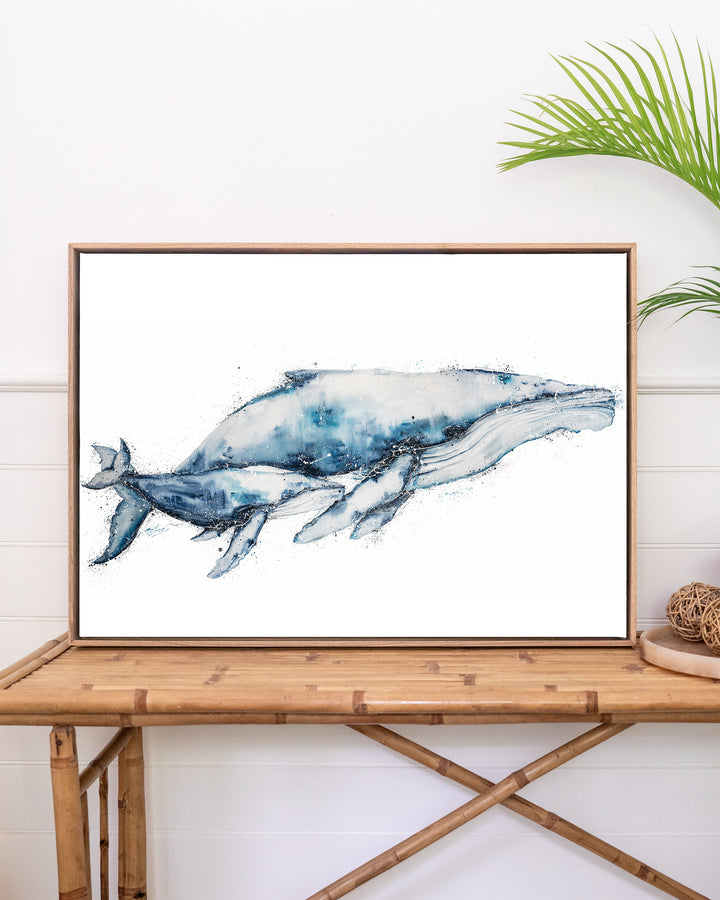Crazy Love humpback whales fine art print by Stephanie Elizabeth, framed canvas in an oak frame above a rattan table