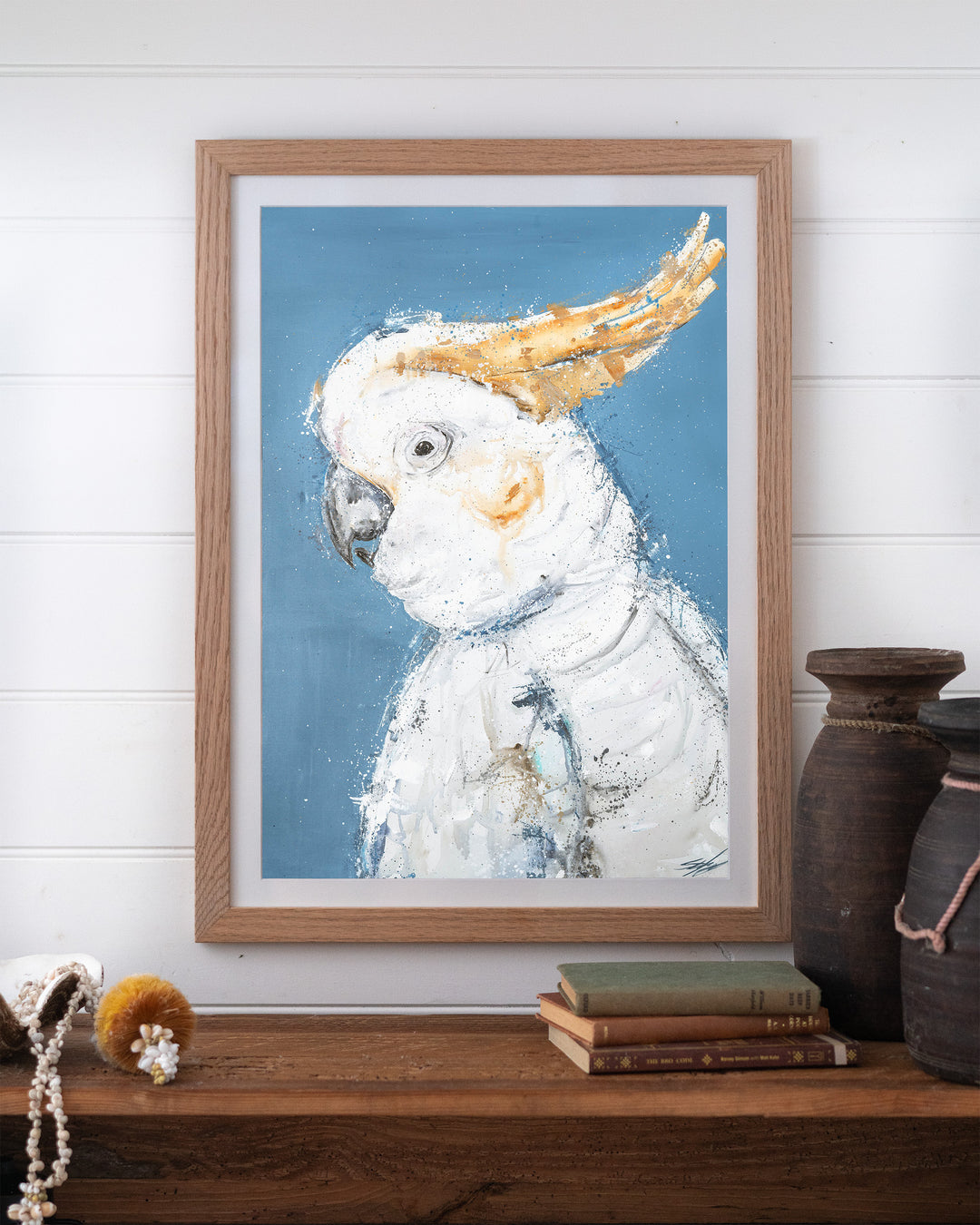Crested Fiesta – white cockatoo, framed paper print in oak frame, styled on a timber shelf