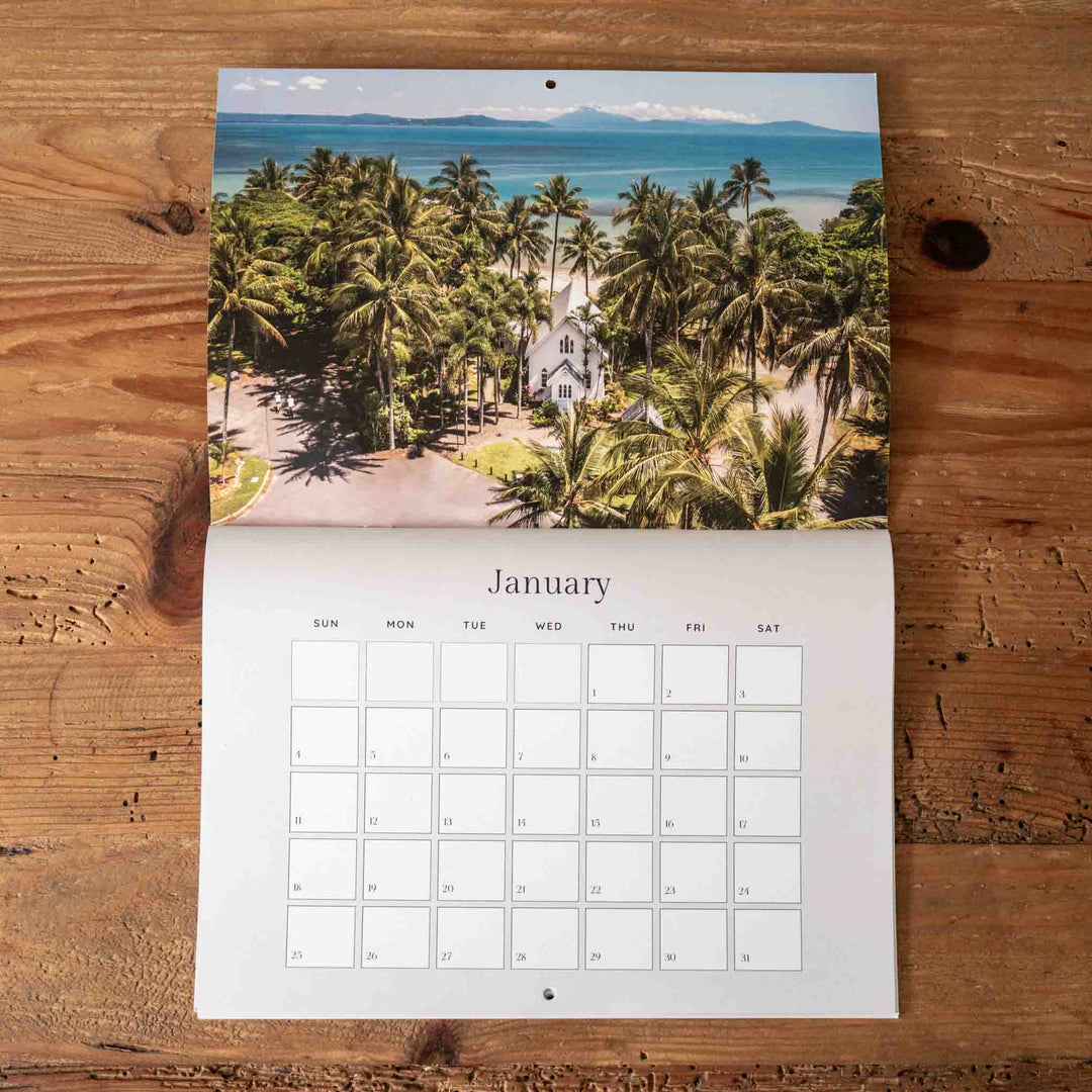 Calendar with a scenic view of palm trees and a church on a wooden surface