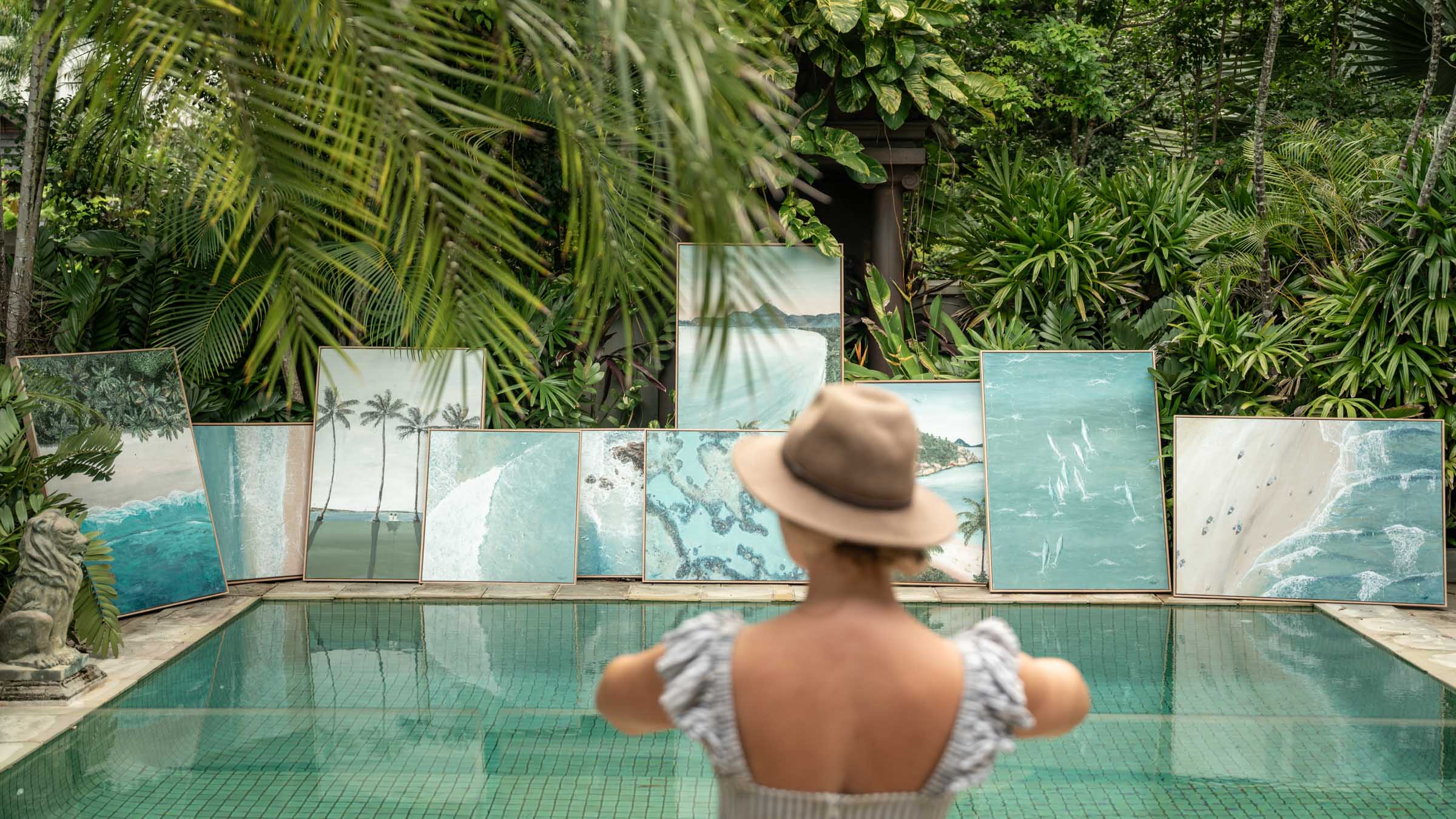 Drift Collection by Stephanie Elizabeth – coastal artworks displayed poolside in a lush tropical garden, featuring soft blue and green ocean tones, aerial beach scenes and relaxed Far North Queensland atmosphere