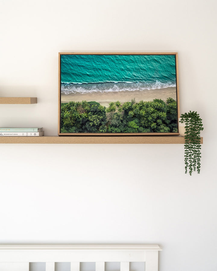 Emerald Tide – Four Mile Beach, Aerial Photography by David Lloyd, framed canvas print in oak float frame, styled in a timber shelf setting