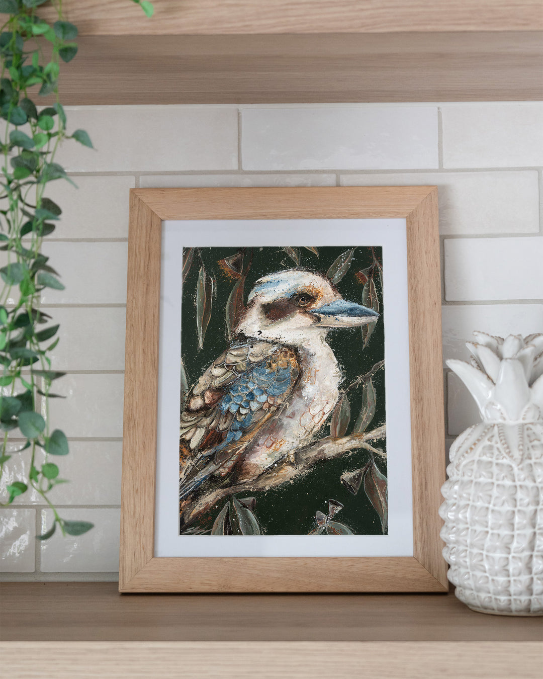 Fablewood kookaburra fine art print by Stephanie Elizabeth, framed paper print in an oak frame on a kitchen shelf