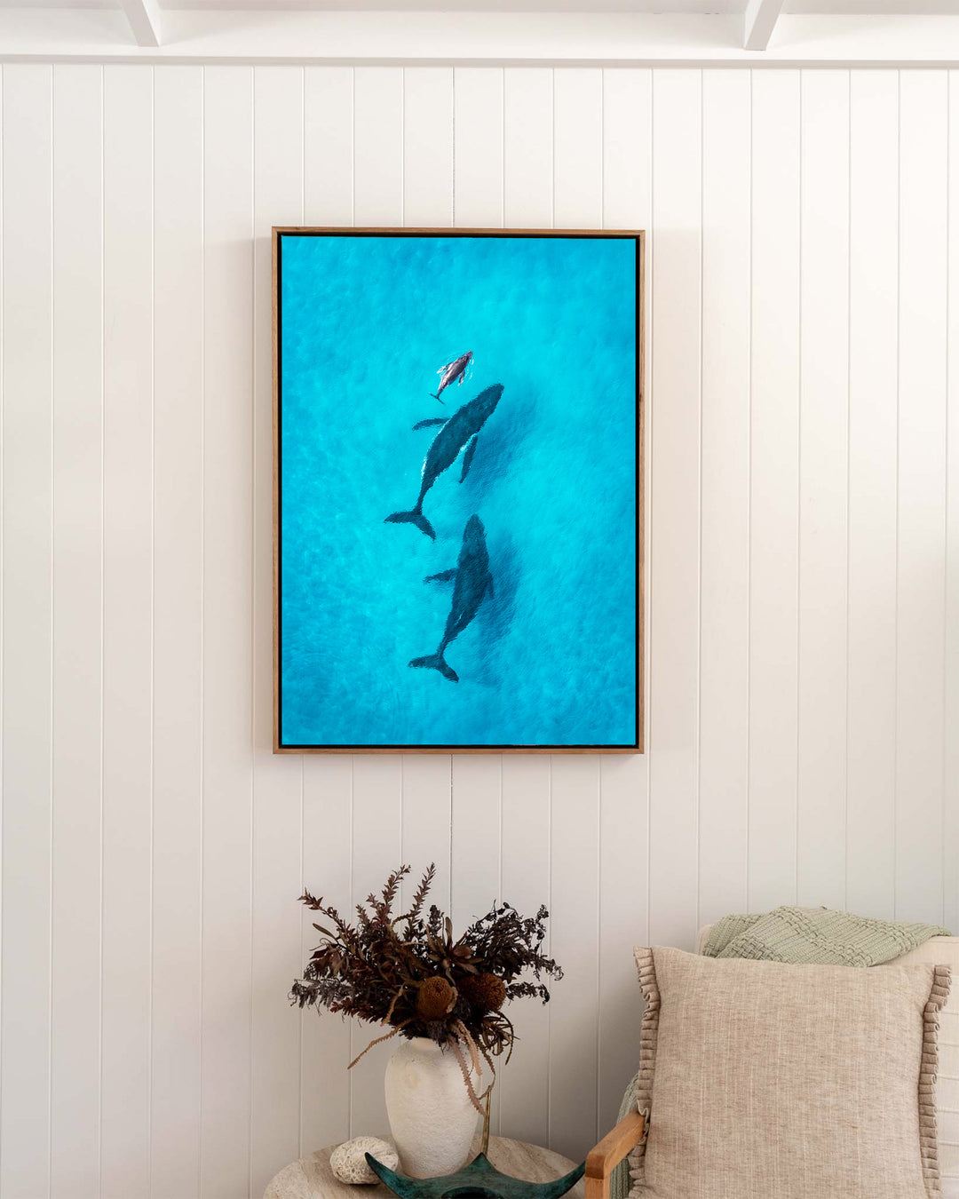 Family Time – Whales, Aerial Photography by David Lloyd, framed canvas print in oak float frame, styled in a bedroom setting