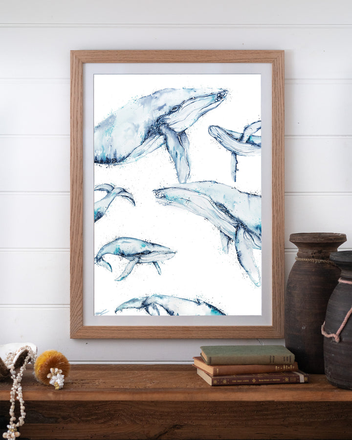 Family Trip humpback whales fine art print by Stephanie Elizabeth, framed paper print in an oak frame on a shelf