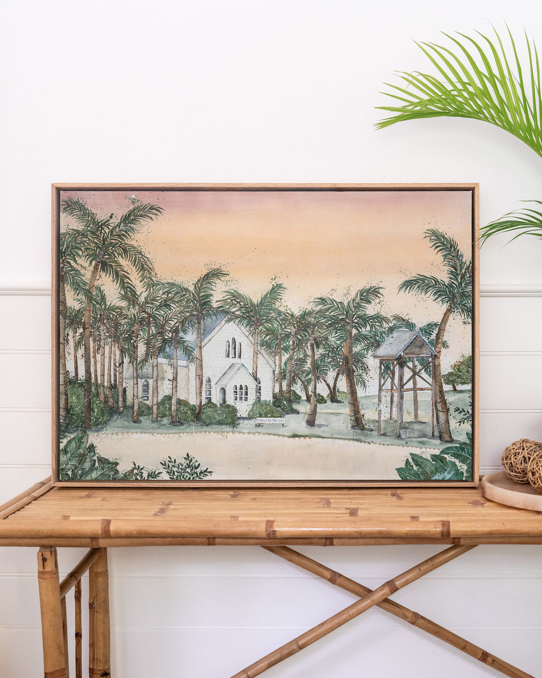 Far Northern Skies – Port Douglas landscape, framed canvas in oak float frame, styled on a rattan table