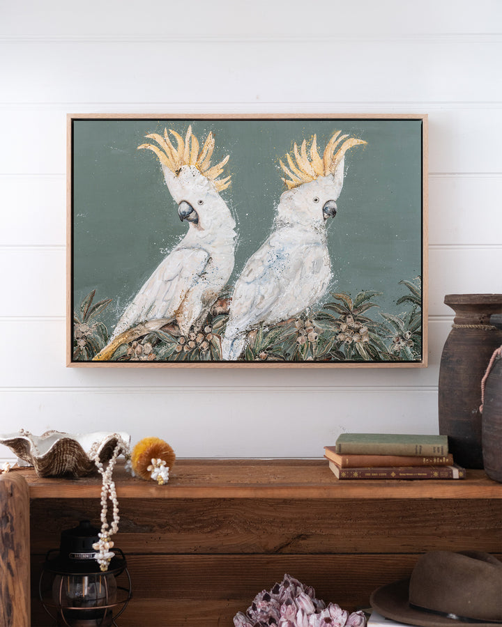 Feathers and Mayhem white cockatoo fine art print by Stephanie Elizabeth, framed canvas in an oak frame above a bookshelf