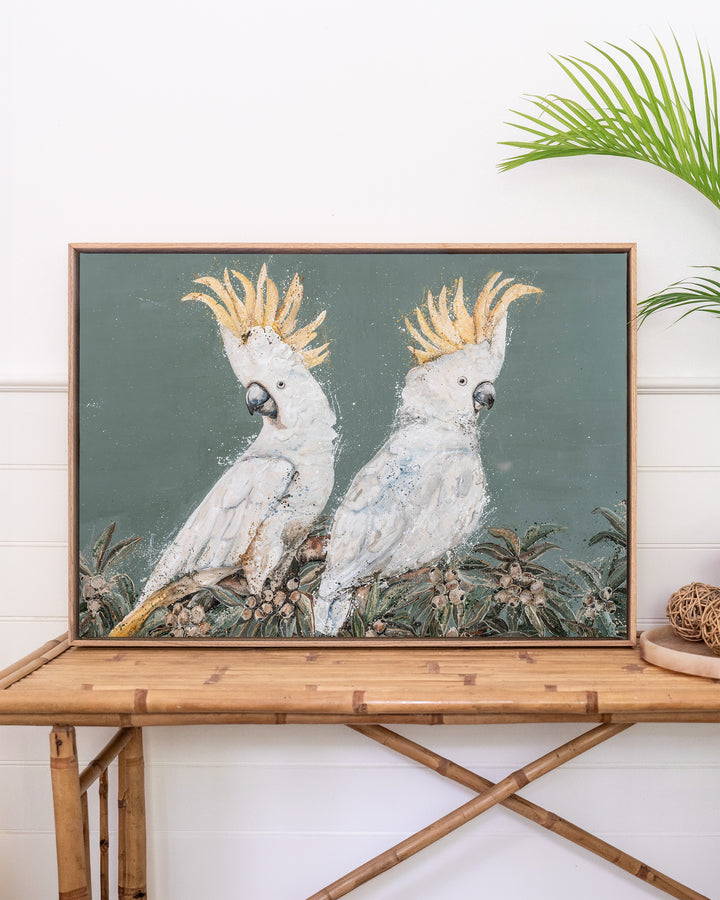Feathers and Mayhem white cockatoo fine art print by Stephanie Elizabeth, framed canvas in an oak frame above a rattan table