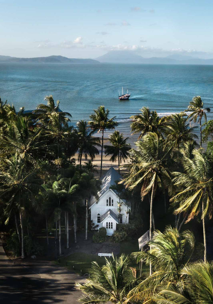 Heading Home – Aerial photograph of St Mary’s Chapel in Port Douglas with palms, ocean views and Shaolin figure in frame | Unframed Rolled Print