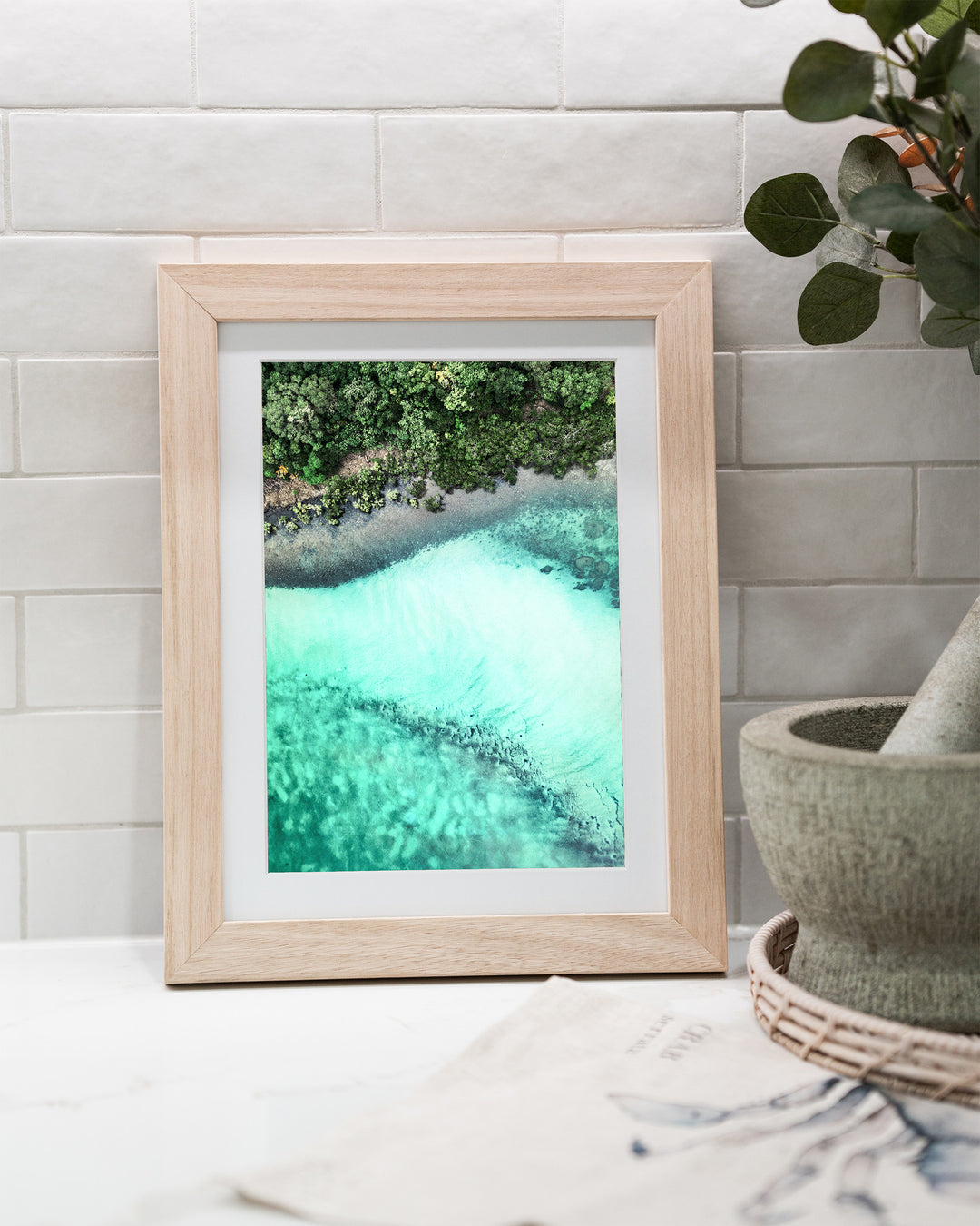 It's Only Natural – Cape Tribulation, Aerial Photography by David Lloyd, framed paper print in oak frame, styled in a kitchen bench setting