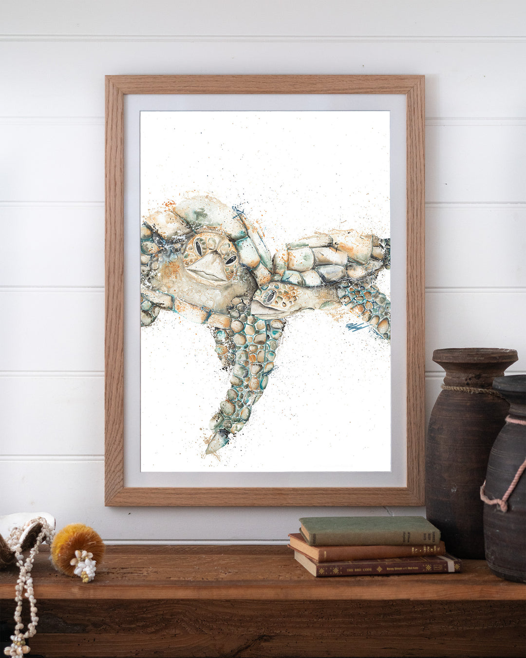 Joined at the Hip – sea turtles, framed paper print in oak frame, styled on a timber shelf