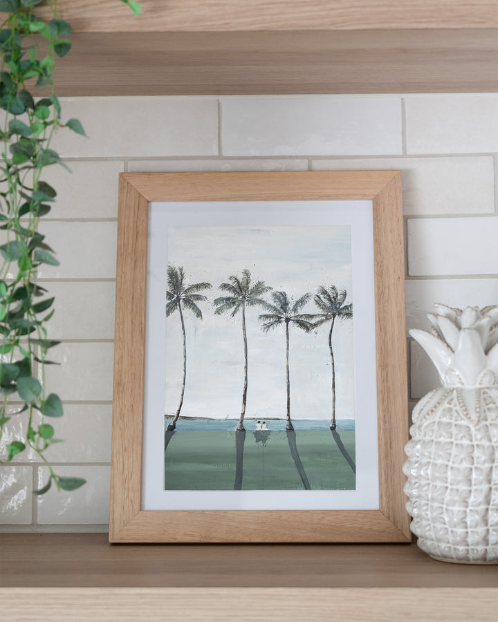 Just Us – palm trees and ocean landscape, framed paper print in oak frame, styled on a kitchen shelf