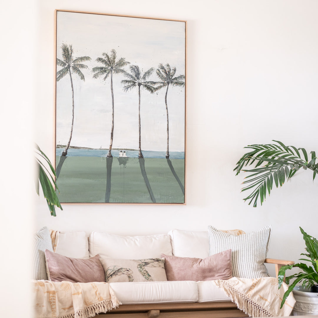 Just Us – original coastal artwork by Stephanie Elizabeth displayed above a sofa in a bright coastal living space with tropical plants