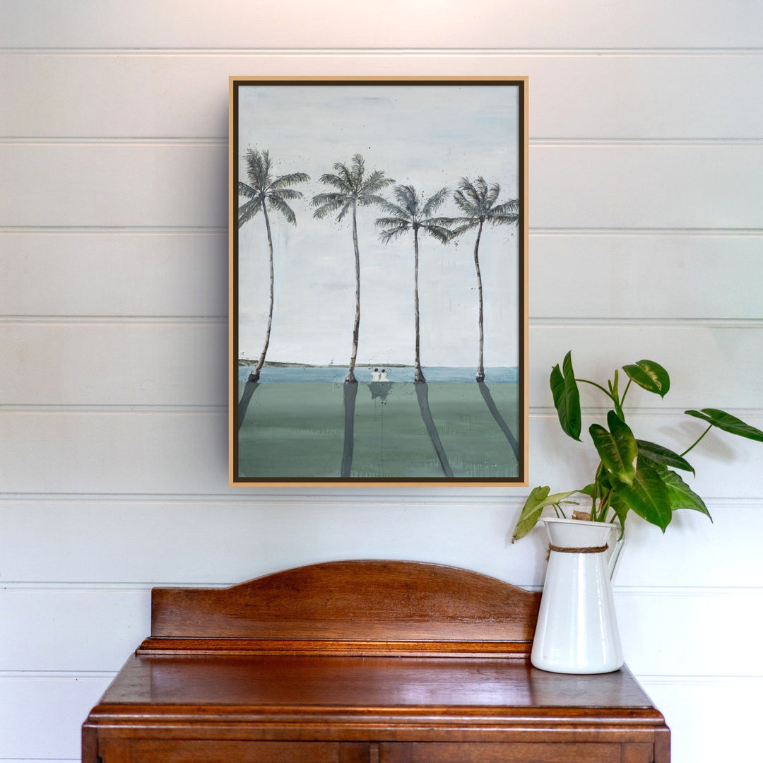 Framed Just Us | Landscape hangs on a white wall above a table with a green potted plant.