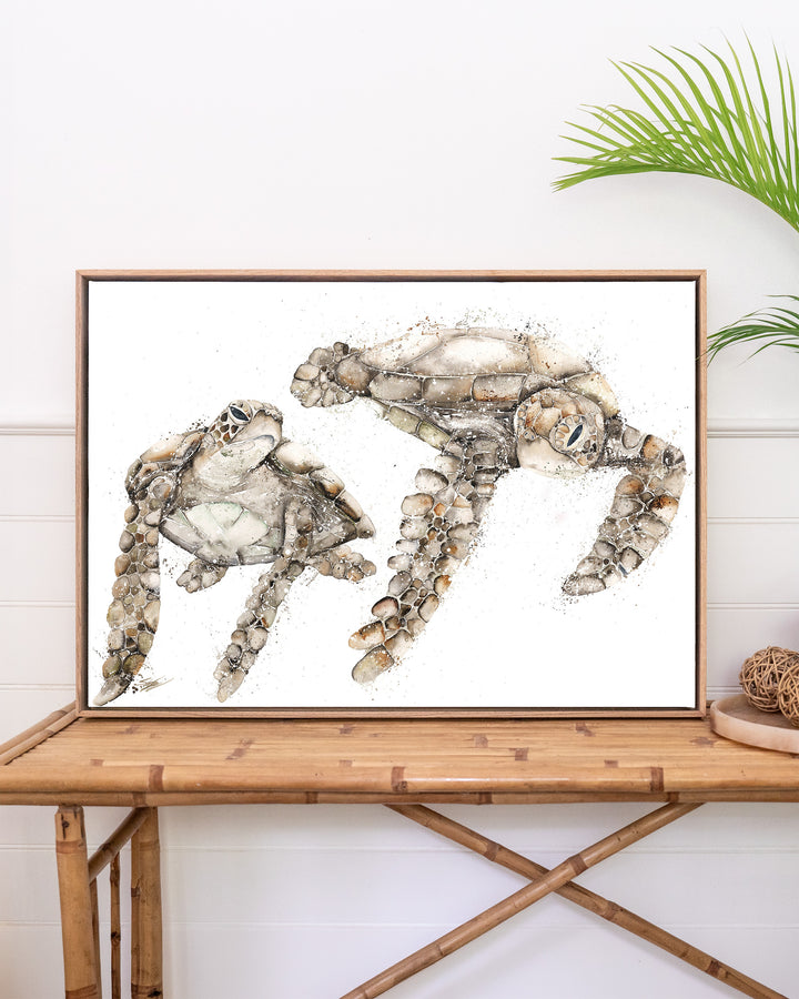 Life by Your Side green sea turtles fine art print by Stephanie Elizabeth, framed canvas in an oak frame above a rattan table