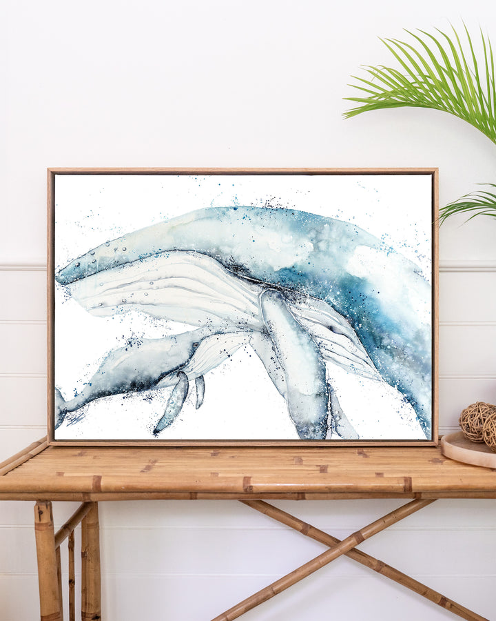 Long Days, Short Years – humpback whale mother and calf, framed canvas in oak float frame, styled on a rattan table