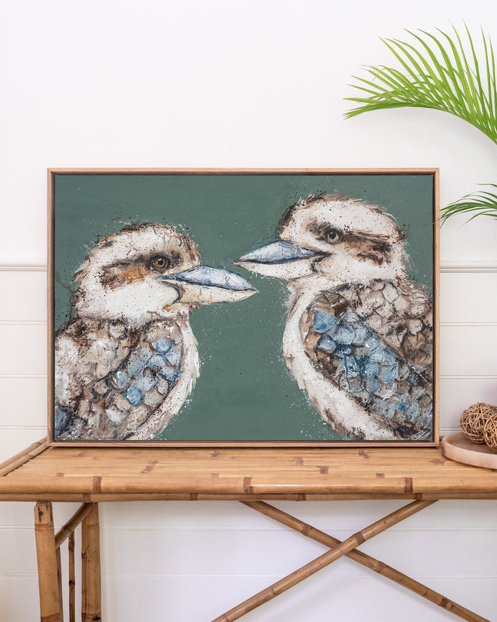 Love Me Now – kookaburras, framed canvas in oak float frame, styled on a rattan table