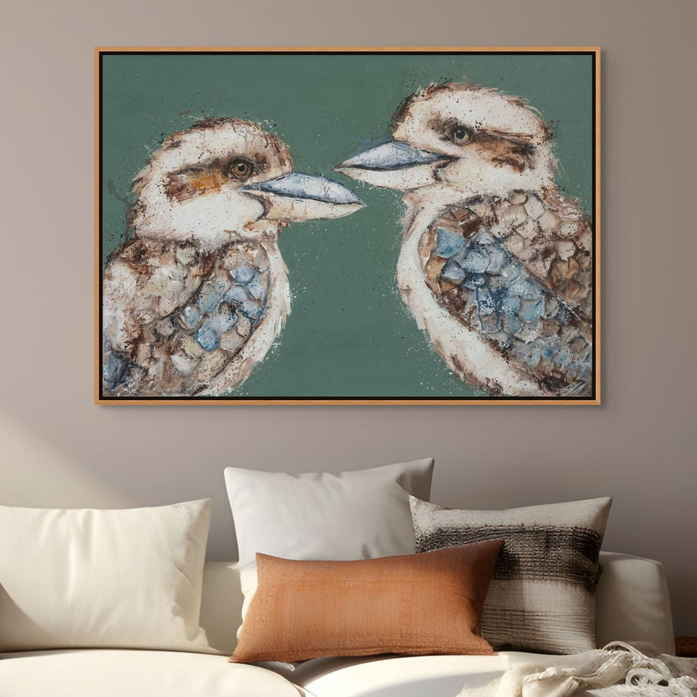 Framed artwork of two kookaburras on a wall above a sofa with pillows.