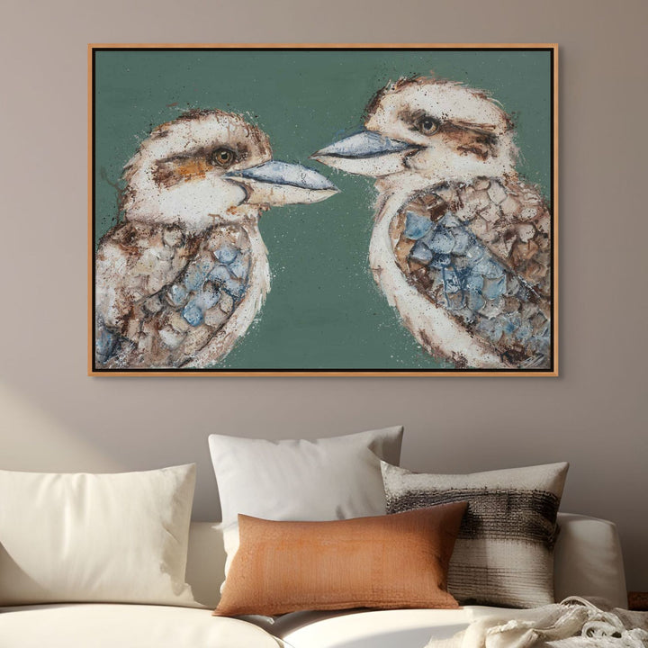 Framed artwork of two kookaburras on a wall above a sofa with pillows.