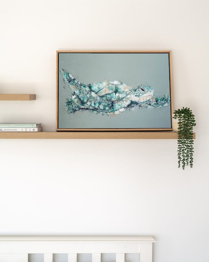 Message in a Bottle green sea turtle fine art print by Stephanie Elizabeth, framed canvas in an oak frame on a shelf