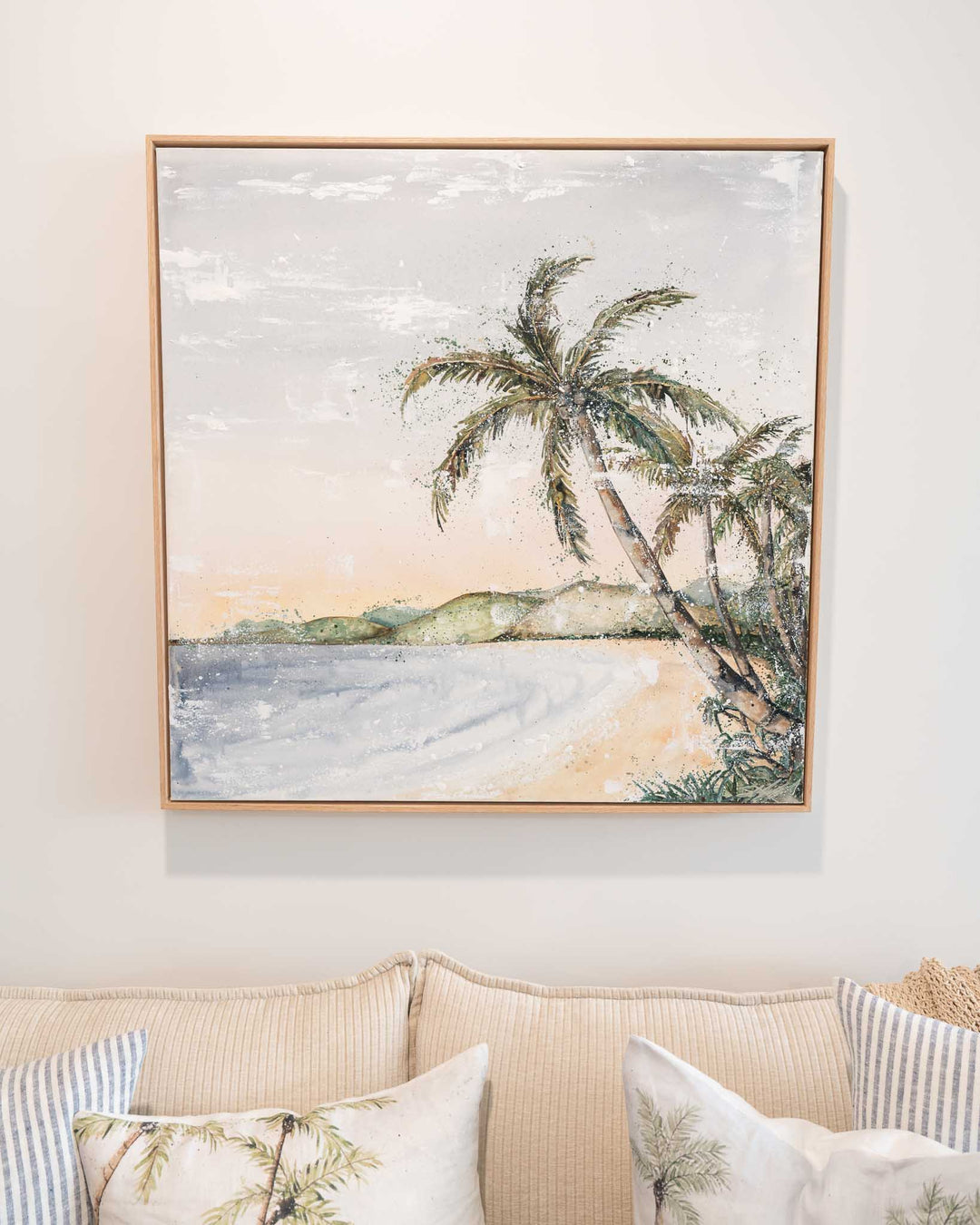 Morning Ritual by Stephanie Elizabeth displayed above a beige couch with green and pink tropical pillows.