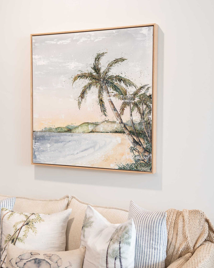 Morning Ritual“ artwork hangs above a beige couch decorated with pillows and a knit throw.
