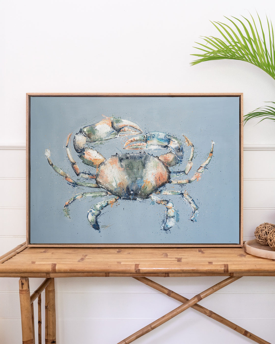 Muddy Days – mud crab, framed canvas in oak float frame, styled on a rattan table