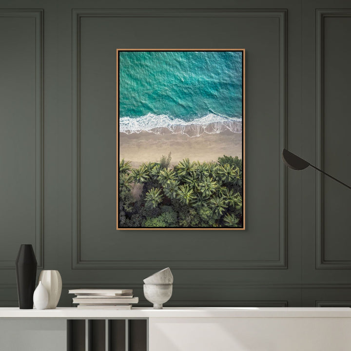 Framed artwork of a beach scene with palm trees on a dark gray wall.
