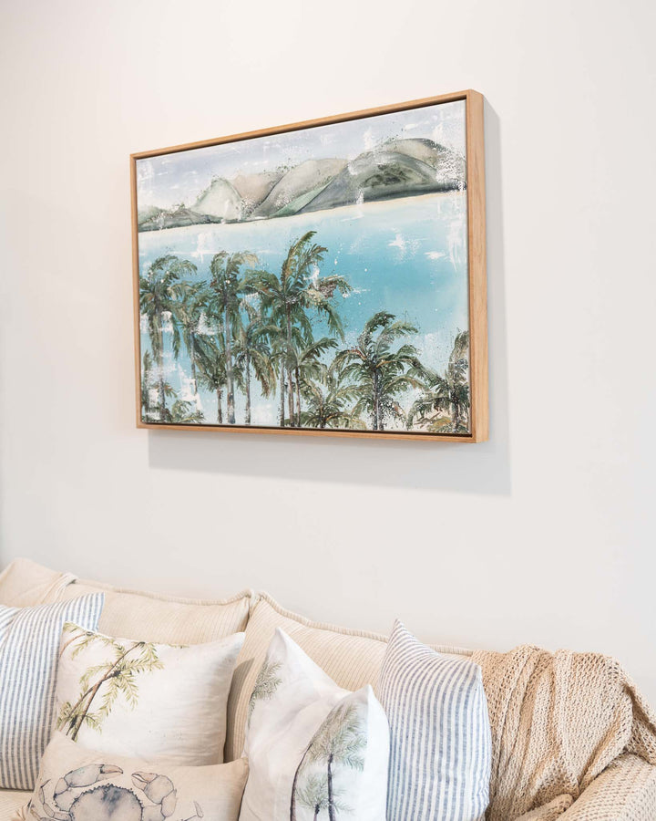“Over Flagstaff” by Stephanie Elizabeth, a tranquil waterside scene displayed above a beige couch.
