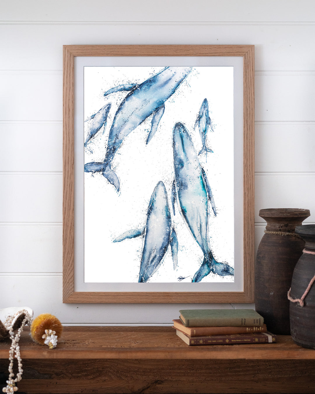 Paving The Way – humpback whales, framed paper print in oak frame, styled on a timber shelf
