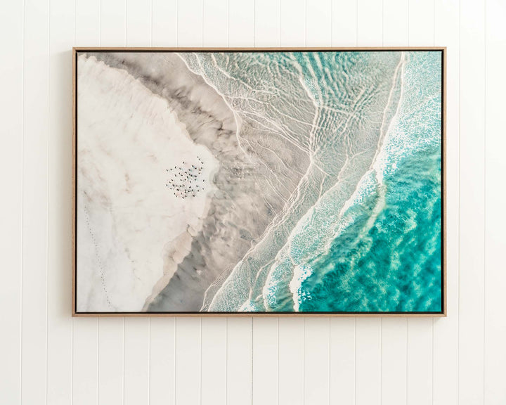 Pearls and Pelicans | Stradbroke Island“ features blue surf and hangs on a white paneled wall.