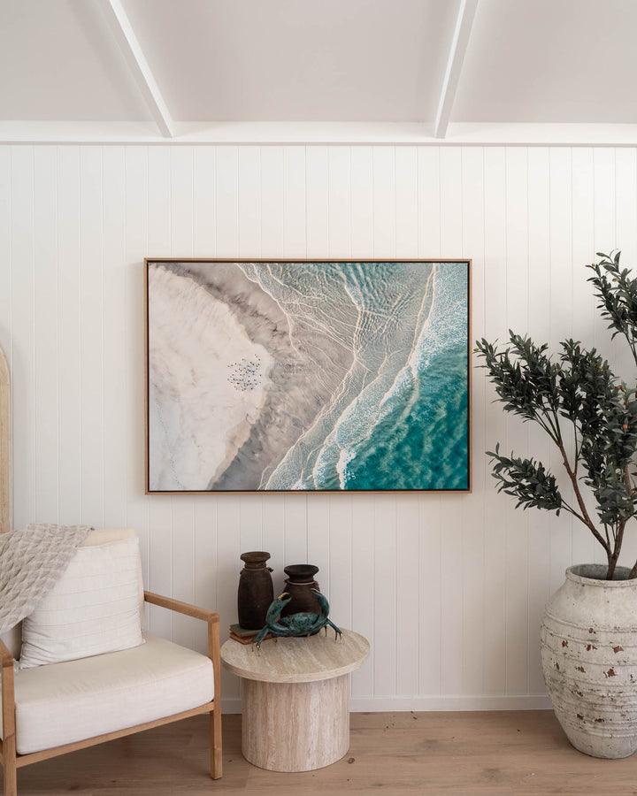 Pearls and Pelicans | Stradbroke Island“ art with pottery accents and a tall potted plant in the display.