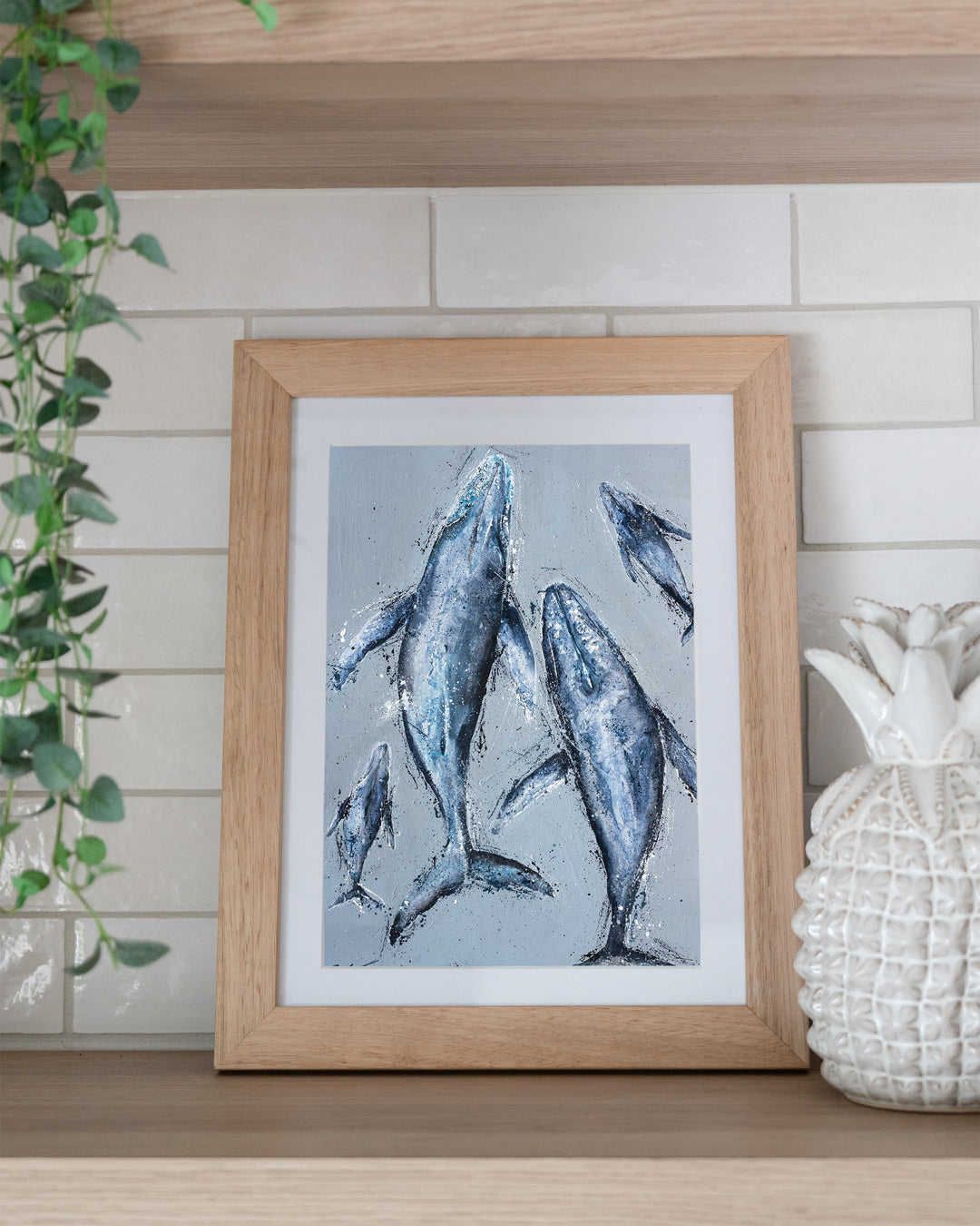 Raise Them on Rhythm and Blues – humpback whales, framed paper print in oak frame, styled on a kitchen shelf
