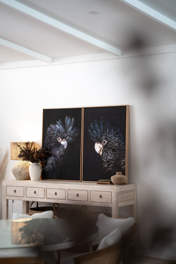 A Little Less Conversation artwork above a light wood console in a modern, minimalist room.
