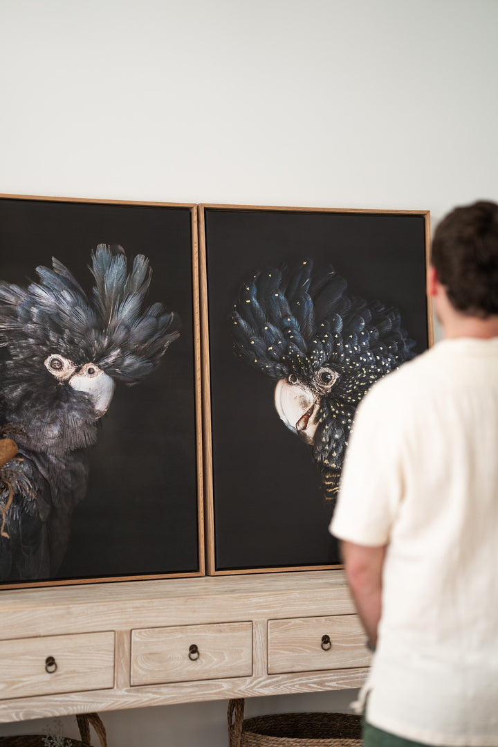 Two “A Little Less Conversation | Black Cockatoo” prints displayed on a console table with someone looking at them.