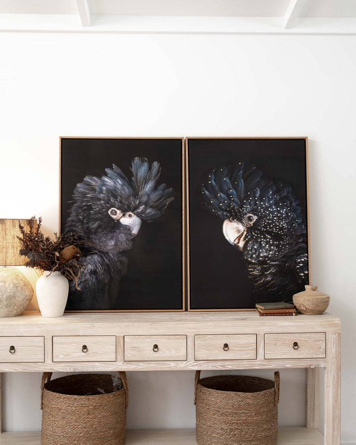 A Little Less Conversation bird portrait on a light wood console with baskets, vases, and dried flowers.