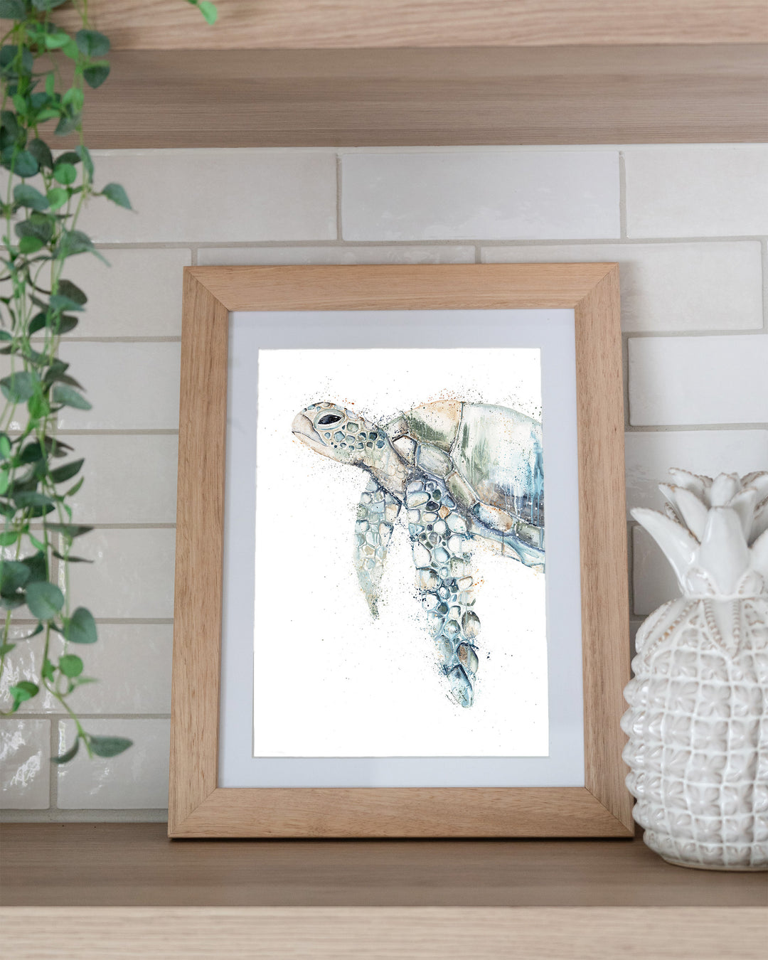 Renegade green sea turtle fine art print by Stephanie Elizabeth, framed paper print in an oak frame on a kitchen shelf