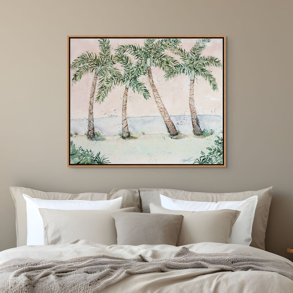 Framed artwork of palm trees on a wall above a bed with beige bedding.