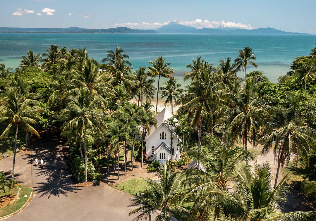 Rolling to the Seaside – Aerial view over St Mary’s, Port Douglas on a perfectly flat day with tropical waters, blue skies, and distant mountains | Unframed Rolled Print