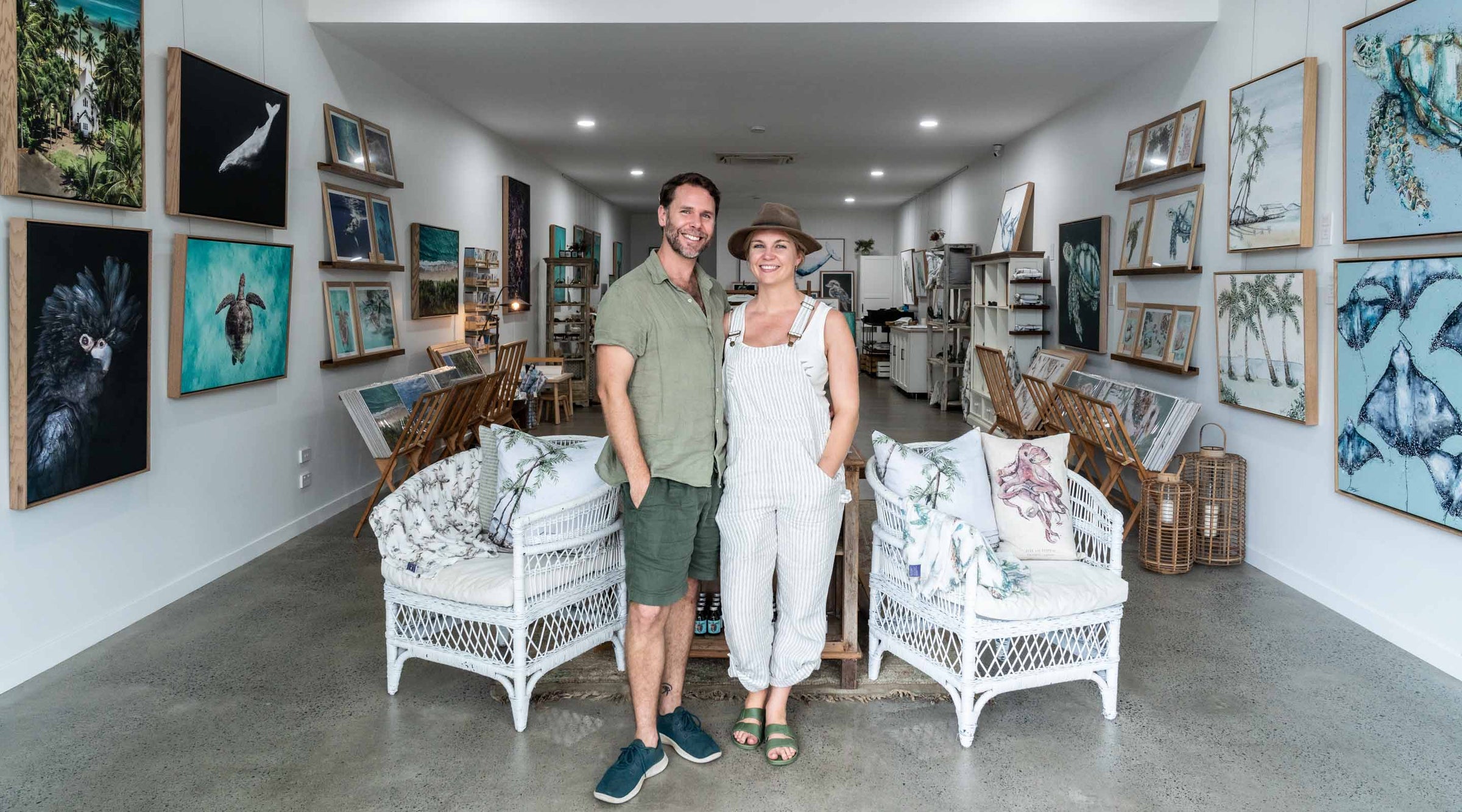 SEA Gallery – Stephanie Elizabeth and David Lloyd standing together in gallery, smiling, warm lighting, artworks in background | Desktop Banner