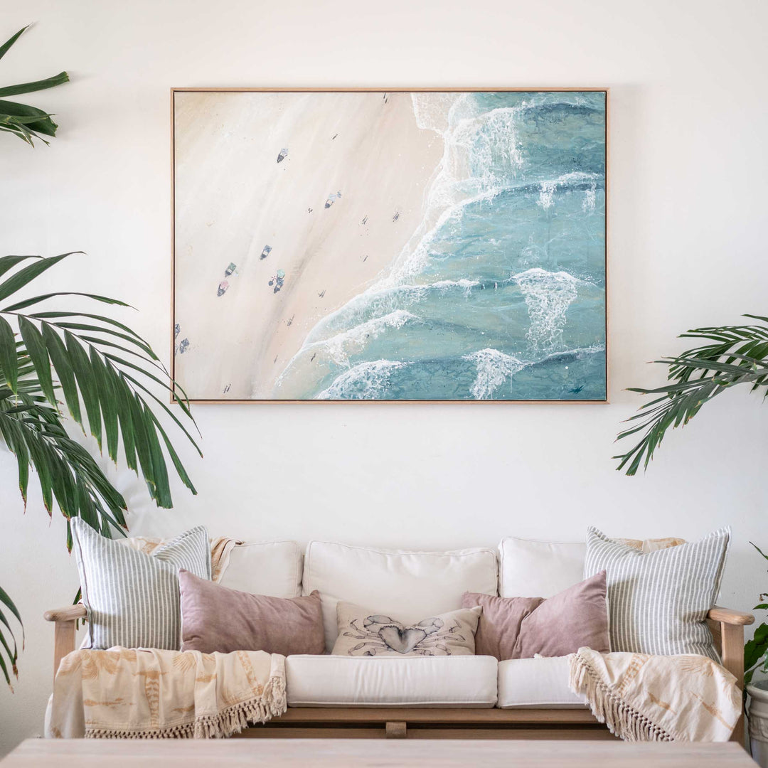 Soaking Up Summer – aerial beach artwork with turquoise waves and sandy shoreline styled above sofa in light coastal interior | Original Artwork