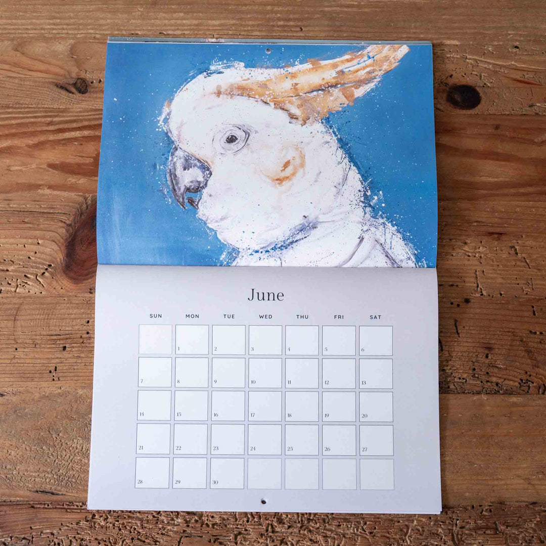 Calendar with a parrot illustration on a wooden surface