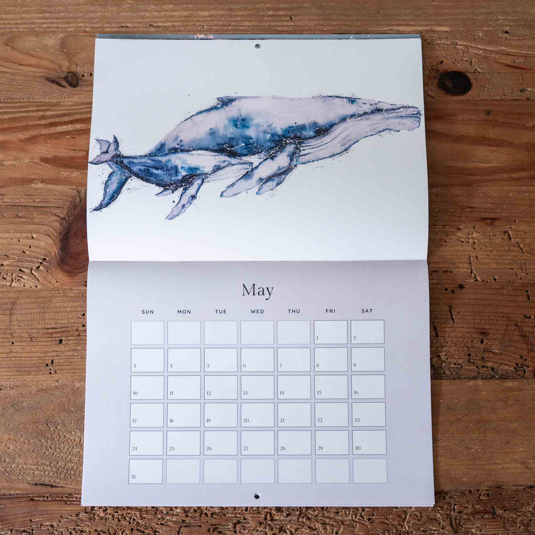Calendar with a whale illustration on a wooden surface