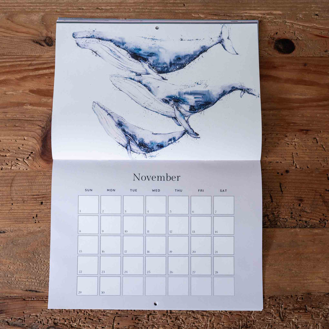 Calendar with whale illustration on a wooden surface