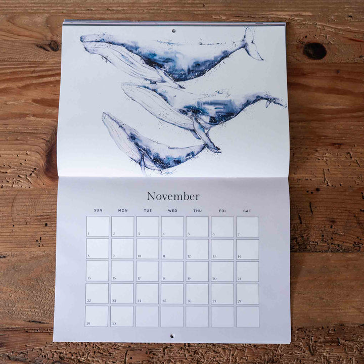 Calendar with whale illustration on a wooden surface