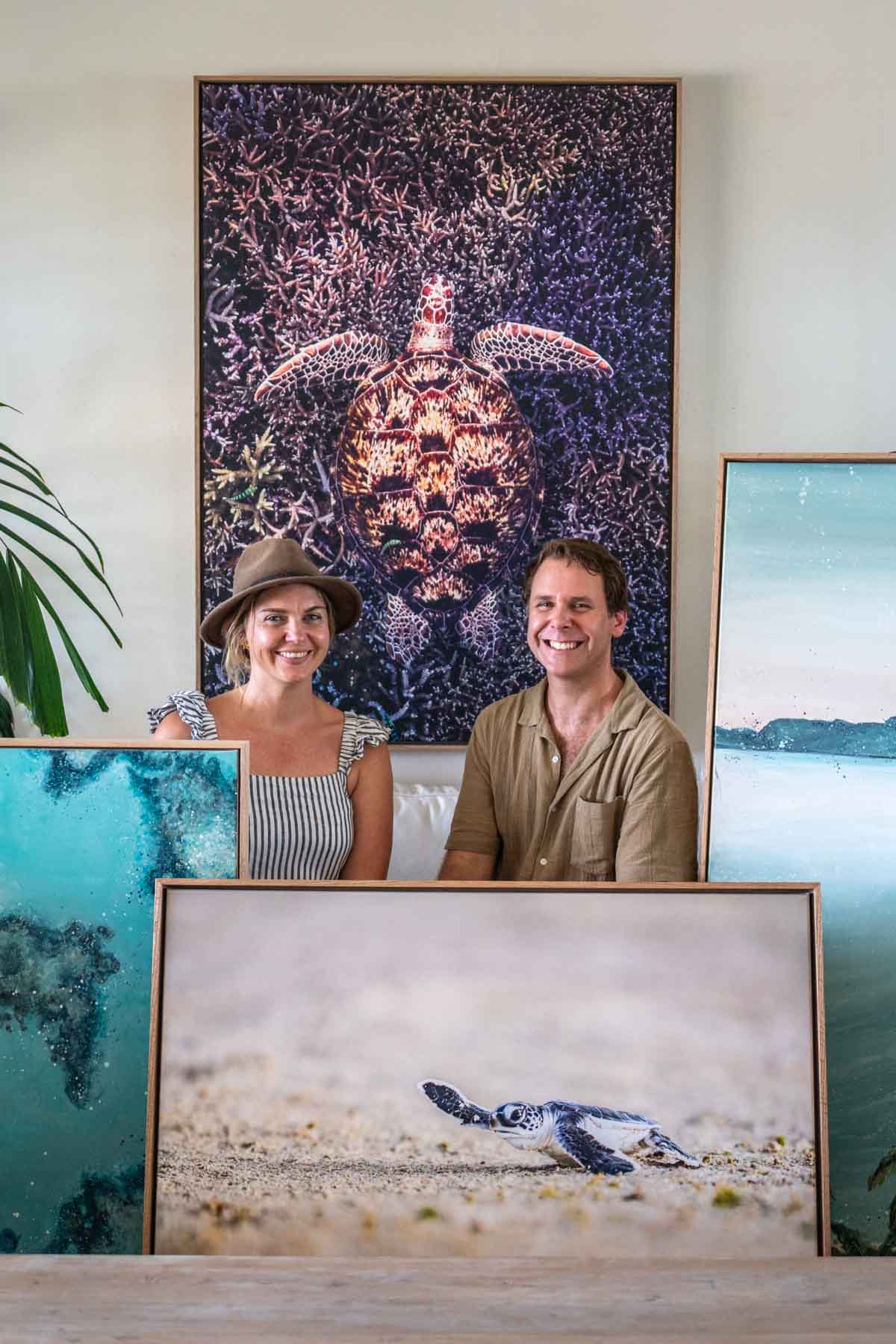 Stephanie Elizabeth and David Lloyd with coastal original artworks and fine art prints, including turtle, reef and beach scenes in a tropical Port Douglas studio setting
