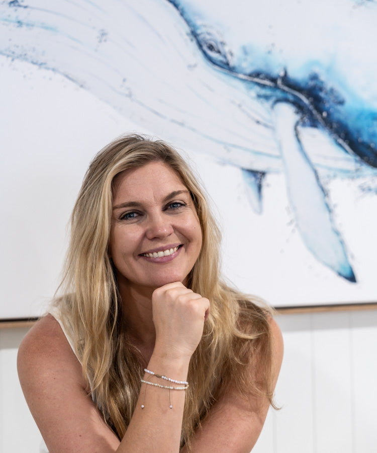 Stephanie Elizabeth smiling in SEA Gallery, standing in front of a large whale artwork | About Section Homepage