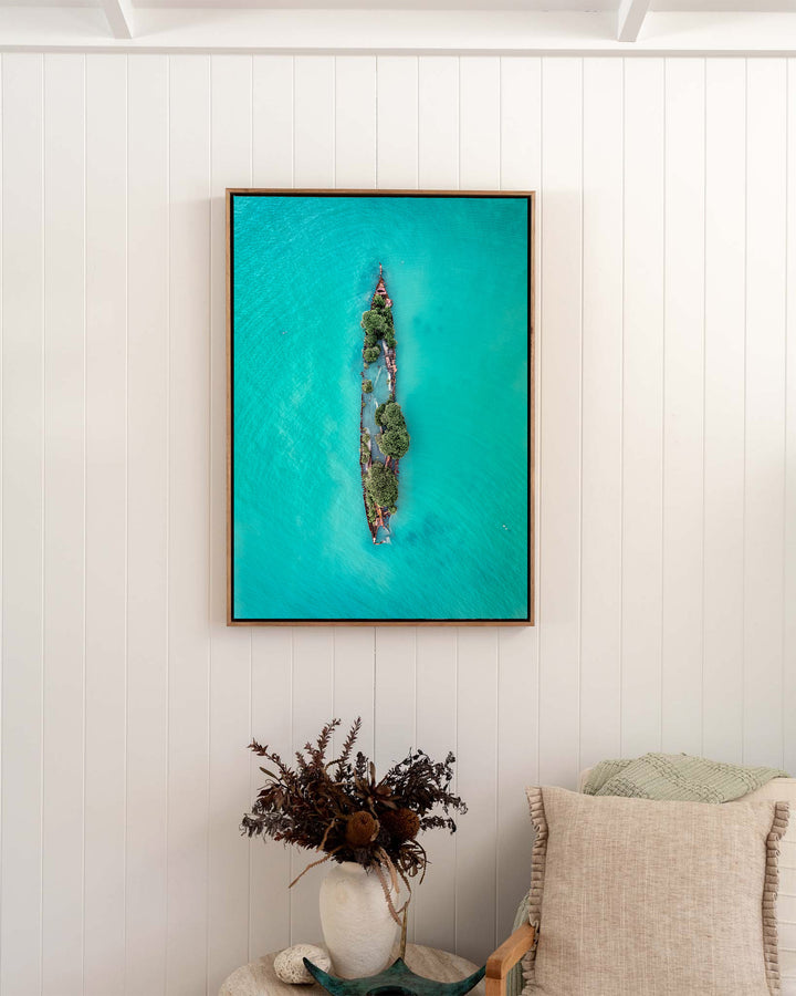Sunken Solitude – Magnetic Island Shipwreck, Aerial Photography by David Lloyd, framed canvas print in oak float frame, styled in a bedroom setting