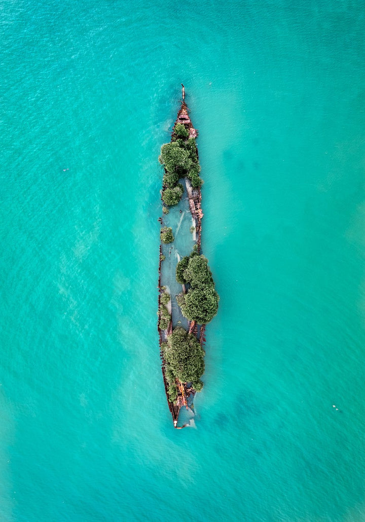Sunken Solitude – Aerial view of a century-old rusted shipwreck surrounded by turquoise waters and mangroves on Magnetic Island, Australia | Unframed Rolled Print