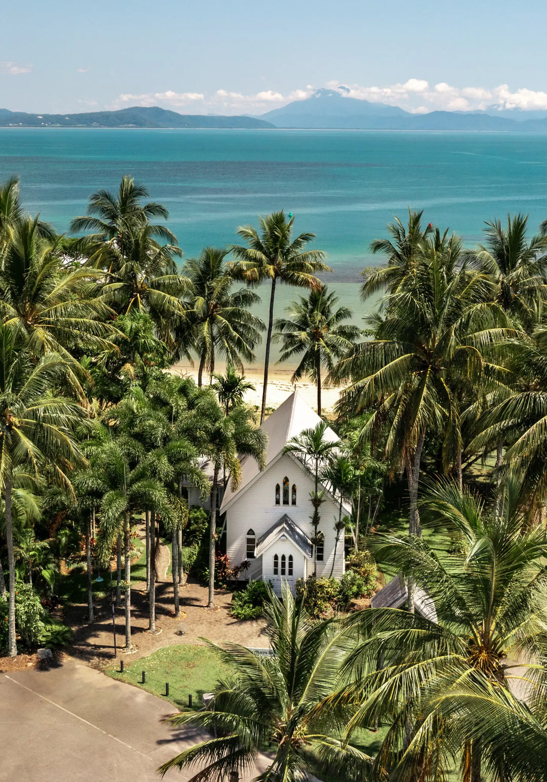 The Art of Loving – bright coastal photograph of St Mary’s Chapel in Port Douglas surrounded by tropical palm trees and ocean backdrop | Unframed Rolled Print